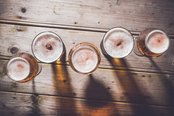 Glasses of beer on an old wooden table. — Stock Photo, Image