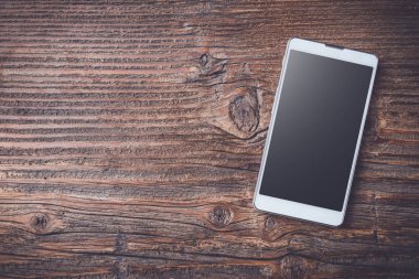 Eski bir ahşap masa beyaz akıllı telefon