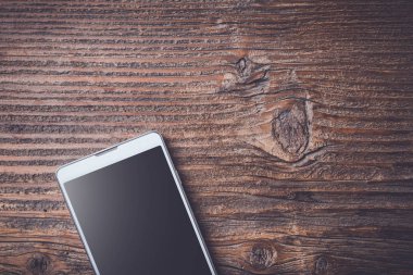Eski bir ahşap masa beyaz akıllı telefon