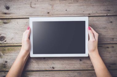Beyaz dijital tablet ahşap masa üzerinde tutan kadın