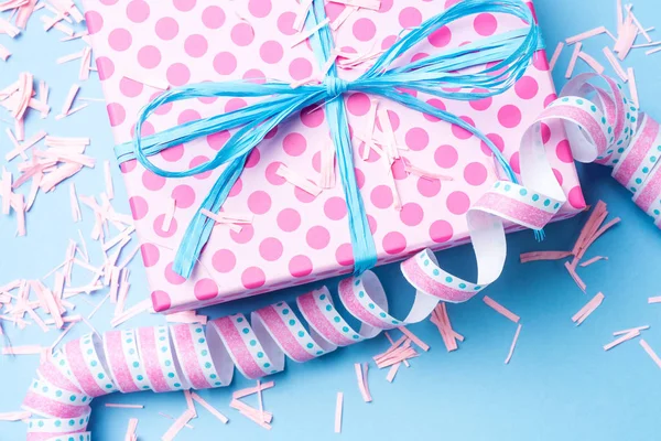 Birthday background with pink dotted gift box, serpentine and confetti on blue background — Stock Photo, Image