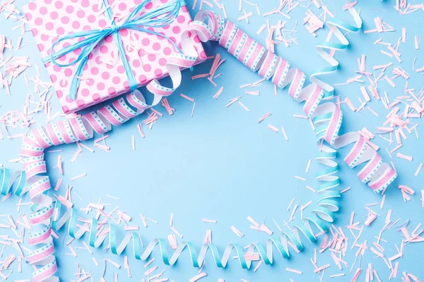 Birthday background with pink dotted gift box, serpentine and confetti on blue background — Stock Photo, Image