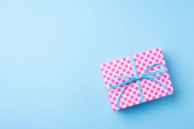 Mavi arka plan üzerinde pembe noktalı hediye kutusu