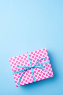 Mavi arka plan üzerinde pembe noktalı hediye kutusu