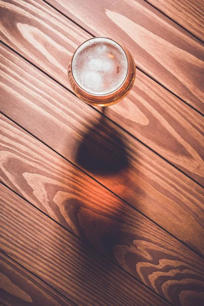 Overhead schot van bierglas op houten tafel. — Stockfoto