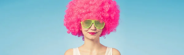 Portrait of beautiful woman in pink wig and green glasses with copy space