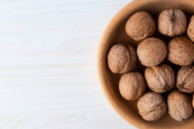 Tahta bir kasede ceviz, açık ahşap bir masa.