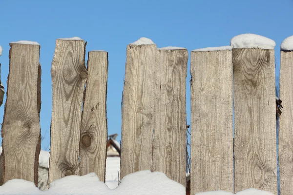 Old wooden fence against snow in the winter Stock Photo