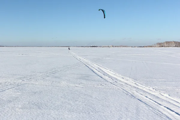 De jonge man met een parachute skiën op een sneeuwveld — Stockfoto