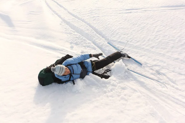 De vrouw toerist met een rugzak liggend op sneeuw na afdaling — Stockfoto