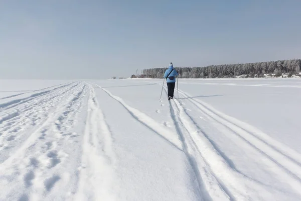 Die Frau in der blauen Jacke beim Skifahren auf dem Schnee des Flusses — Stockfoto