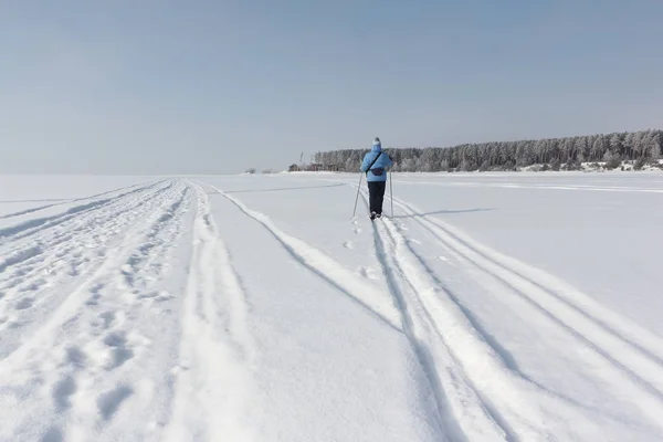 Kvinnan i en blå jacka skidåkning på snö över floden — Stockfoto