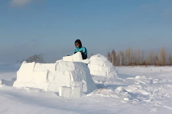 El hombre construyendo un iglú de bloques de nieve en un claro en el invierno — Foto de Stock