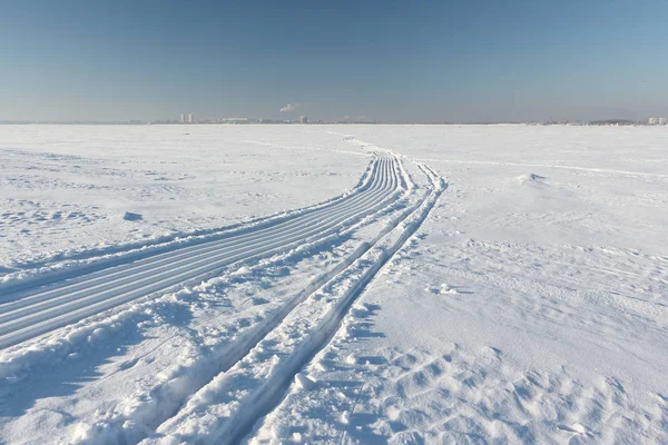 Huella de una moto de nieve y trineo en una superficie nevada de depósito congelado —  Fotos de Stock
