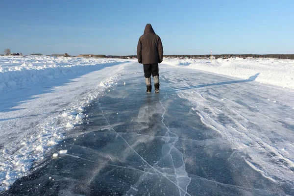Человек идет по ледяной дороге по замерзшему водохранилищу — стоковое фото