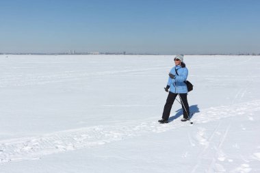 Nordic Walking - yetişkin kadın mavi bir ceket ve karda hiking