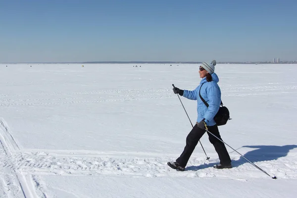 Nordic Walking - yetişkin kadın mavi bir ceket ve karda hiking