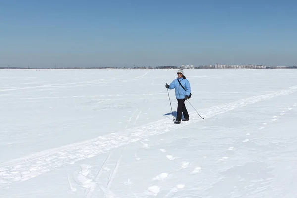 Nordic Walking - volwassen vrouw in een blauwe jas wandelen op sneeuw — Stockfoto