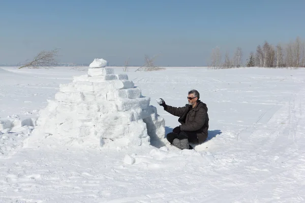 El hombre construyendo un iglú en un claro en el invierno — Foto de Stock