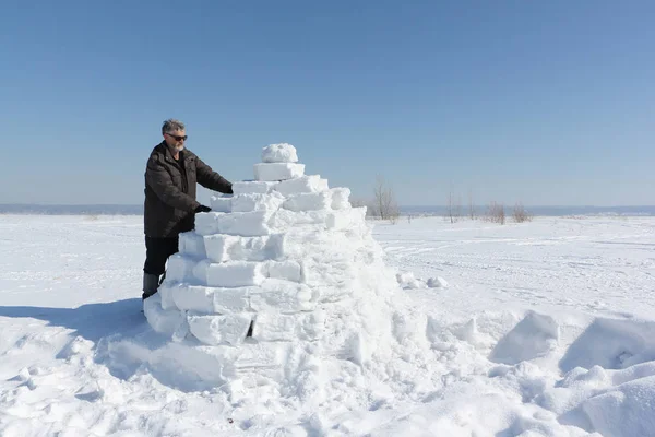 El hombre construyendo un iglú en un claro en el invierno — Foto de Stock
