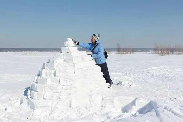 妇女在蓝色夹克建立一个冰屋在雪空地上 — 图库照片