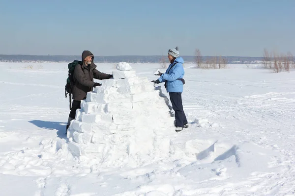 Man and woman building an igloo on a snow glade in the winter — Stock Photo, Image