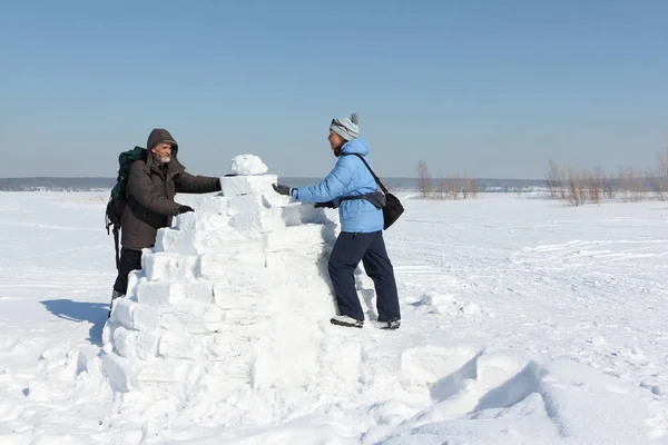 Hombre y mujer construyendo un iglú en un claro de nieve en el invierno — Foto de Stock