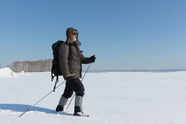 Nordic Walking - volwassen man met een rugzak wandelen op sneeuw — Stockfoto