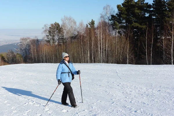 Nordic Walking - vrouw in een blauwe jas wandelen op sneeuw onder mou — Stockfoto