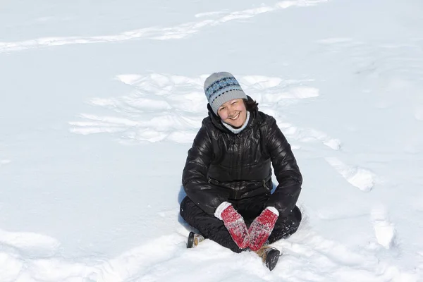 Fröhlich lächelnde Frau hockt im Schneidersitz auf Schnee — Stockfoto