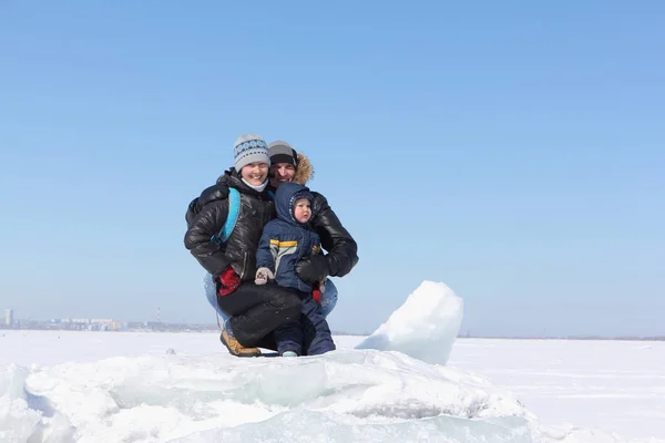 Zittend op een pakijs op een bevroren rivier in de winter en gelukkige familie — Stockfoto