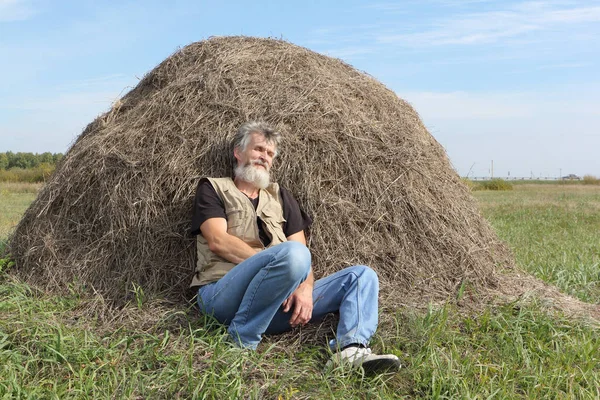 Uomo che dorme in un campo vicino a un pagliaio in autunno — Foto Stock