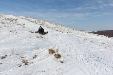 Bir plastik kızak ile bir dağ tırmanma siyah ceketli adamı 
