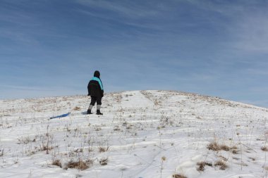 Bir plastik kızak ile bir dağ tırmanma siyah ceketli adamı 