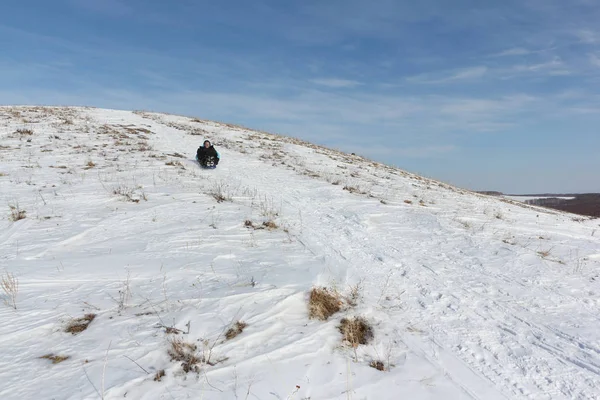 Bir plastik kızak ile bir dağ tırmanma siyah ceketli adamı 