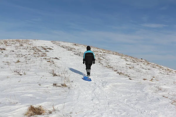 Bir plastik kızak ile bir dağ tırmanma siyah ceketli adamı 