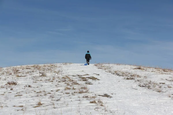 Bir plastik kızak ile bir dağ tırmanma siyah ceketli adamı 