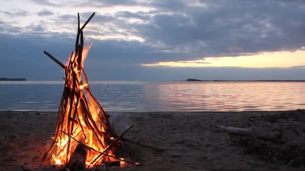 Ognisko w formie namiotu, nagrywanie na brzegu rzeki na zachód słońca — Wideo stockowe