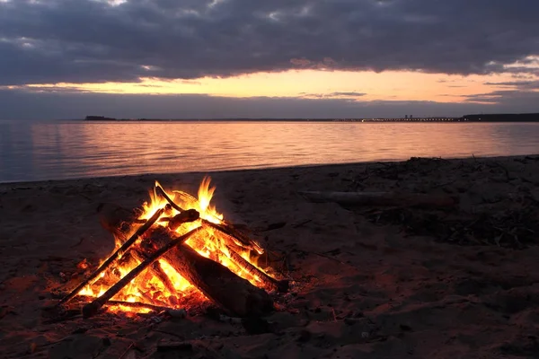 Feuer brennt am Ufer des Flusses bei Sonnenuntergang — Stockfoto