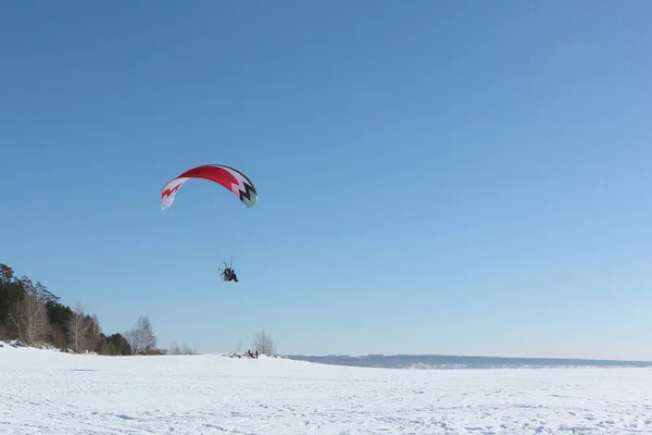 Man met een parachute en een motor, vliegen in de lucht op een winter — Stockfoto