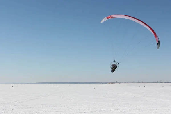 Homme avec un parachute et un moteur, volant dans le ciel en hiver — Photo