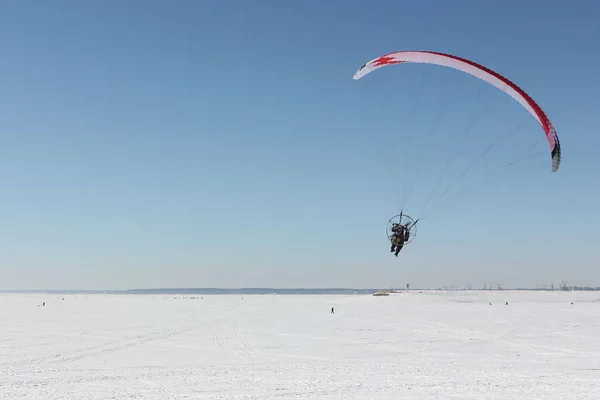 Homem com um paraquedas e um motor, voando no céu em um inverno — Fotografia de Stock