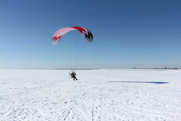 Homem com um paraquedas e um motor, voando no céu em um inverno — Fotografia de Stock