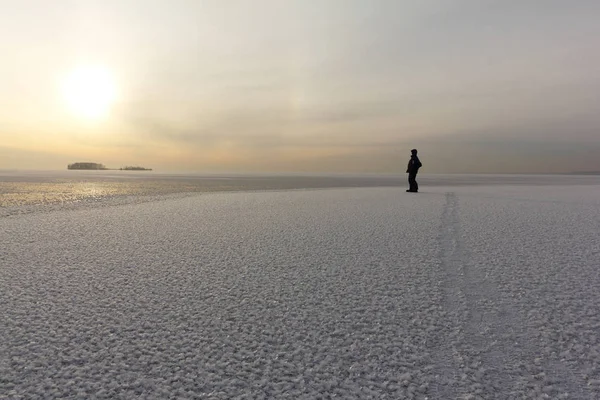 Homem andando sobre um gelo fino de uma lagoa gelada ao pôr do sol — Fotografia de Stock