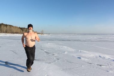 Man in a cap with a naked torso running across the ice of a river clipart