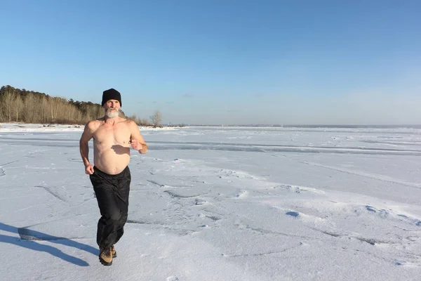 Człowiek w czapkę z nagi tors, uruchomiona na lodzie rzeki — Zdjęcie stockowe