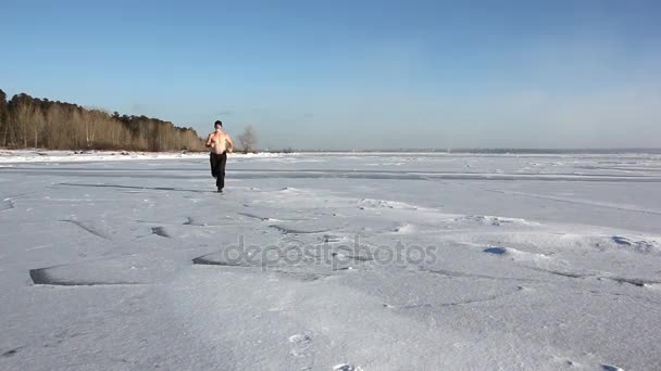 凍った川 貯水池 ロシアの氷の上を実行している 裸の胴体とキャップの男 — ストック動画