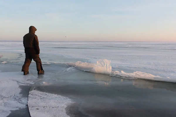 Hombre con ropa de abrigo caminando por el delgado hielo de un río congelado — Foto de Stock