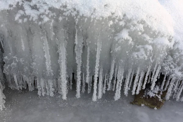 Ijspegels in rime op een steen op een ijskoude rivier — Stockfoto