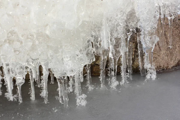 Icicles in  rime on a stone on a freezing river — Stock Photo, Image